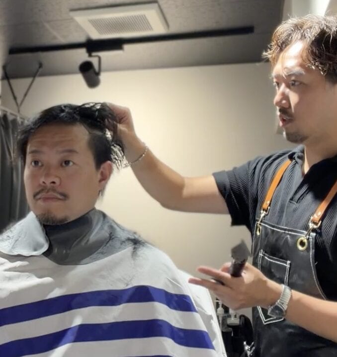 つむじ周辺の毛流れを確認しながらカットする40代男性の施術中