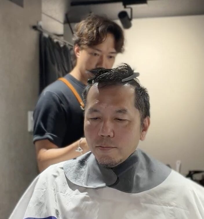 頭頂部とつむじ薄毛を毛流れでカバーする40代男性の施術途中